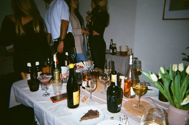 A dinner party table covered in bottles and glasses, shot on CATCH film